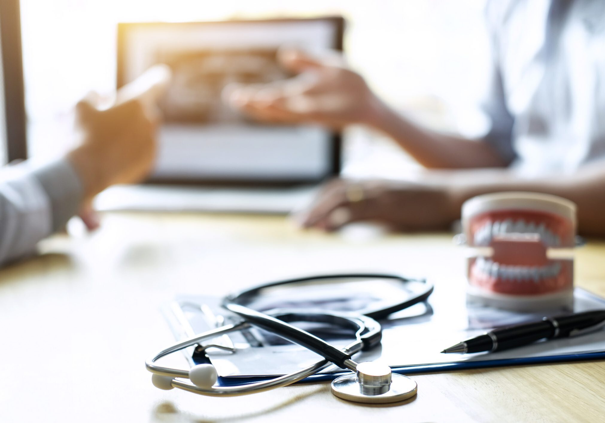Stethoscope and dental model on desk.